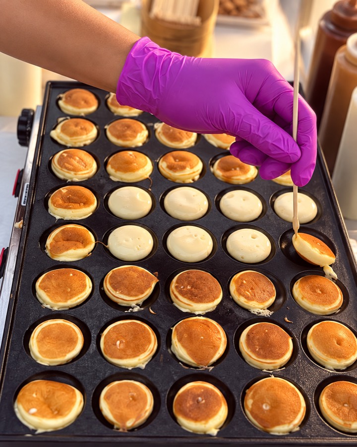 Mini pancakes en pleine cuisson sur la plaque, retournés un par un